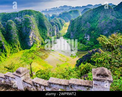 Impressionnantes formations karstiques et rizières à Tam Coc avec l'escalier en pierre montant le dragon couché au premier plan, province de Ninh Binh, VI Banque D'Images