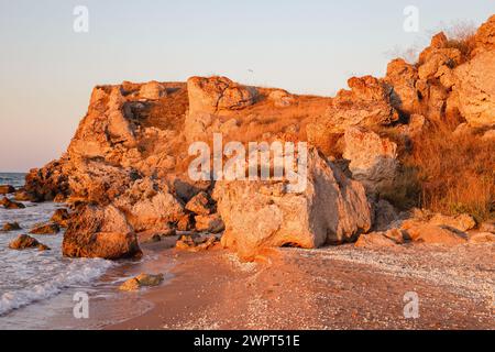 Roches rouges illuminées par le soleil couchant sur la côte de la mer d'Azov. Voyages et tourisme. Banque D'Images