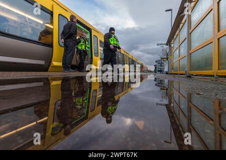 Les passagers qui partent et montent dans un train Merserail à la gare de Bebington se reflètent dans une flaque d'eau Banque D'Images