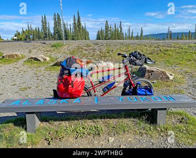 Banc juste à la frontière entre l'Alaska et le Yukon, vélo de randonnée emballé, voyage d'aventure, Alaska Highway, territoire du Yukon, Canada Banque D'Images