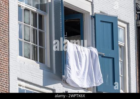Gros plan d'une fenêtre ouverte avec des volets bleus et une chemise blanche, Middelburg, Zélande, pays-Bas Banque D'Images