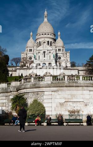 Vue sur les dômes et les tours de la façade sud de la Basilique du Sacré coeur de Montmartre depuis le Square Louise Michel avec les gens assis Banque D'Images