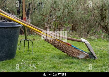 Outils de jardinage. Balai, pelle et râteau sur pot de fleurs dans le jardin. À l'extérieur. Banque D'Images