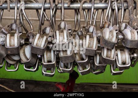 Un tas de poulies en plastique anciennes et usagées suspendues à un poteau par des crochets métalliques, dans un magasin d'articles recyclés de la ville de Barbosa, dans le centre de la Colombie. Banque D'Images
