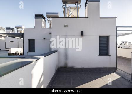 Grenier d'une maison unifamiliale, réseaux d'eau chaude photovoltaïque et sol en grès gris sur une journée avec un ciel dégagé Banque D'Images