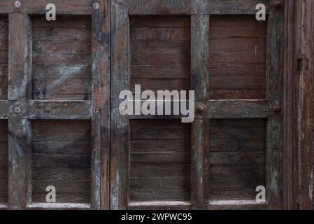 Une vieille porte en bois lambrissée avec des clous en métal et de la peinture foncée Banque D'Images