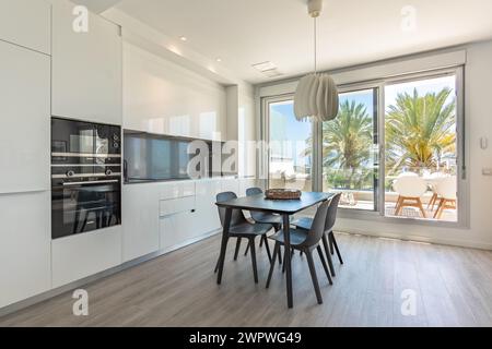 une image d'une table à manger noire à côté d'une cuisine nouvellement finie dans l'immobilier méditerranéen Banque D'Images