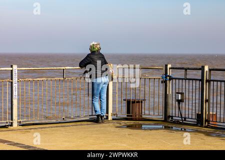 Southwold, Suffolk, 9 mars 2024, Une dame regarde vers la mer au soleil de Southwold Pier, Suffolk, les prévisions sont pour la pluie demain. Typiquement, c'est une moyenne de 7C à cette époque de l'année, mais il était de 11C cet après-midi. Crédit : Keith Larby/Alamy Live News Banque D'Images