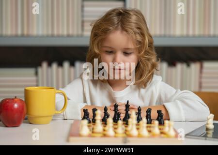 Enfant garçon concentré développant la stratégie d'échecs, jouant à un jeu de société Banque D'Images