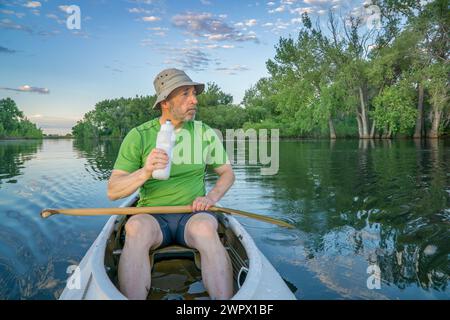 Pagayeur mâle senior dans un canoë d'expédition sur un lac calme dans le nord du Colorado Banque D'Images