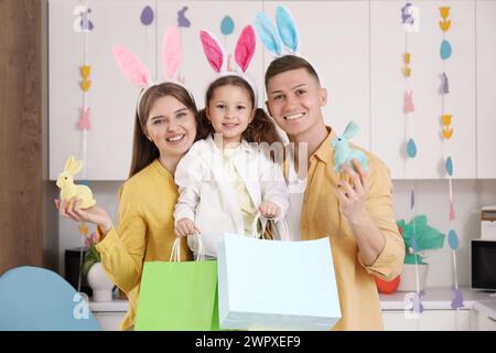 Famille heureuse avec des sacs à provisions et des lapins de jouet dans la cuisine. Soldes de Pâques Banque D'Images