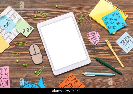 Tablette, clavier d'ordinateur, souris de carton et notes adhésives. Farce du jour des fous d'avril Banque D'Images