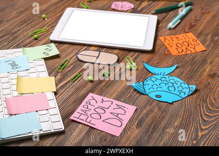 Tablette, clavier d'ordinateur, souris de carton et notes adhésives. Farce du jour des fous d'avril Banque D'Images