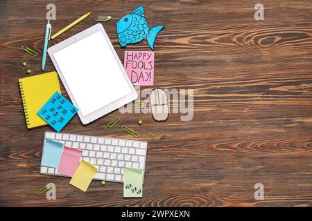 Tablette, clavier d'ordinateur, souris de carton et notes adhésives. Farce du jour des fous d'avril Banque D'Images