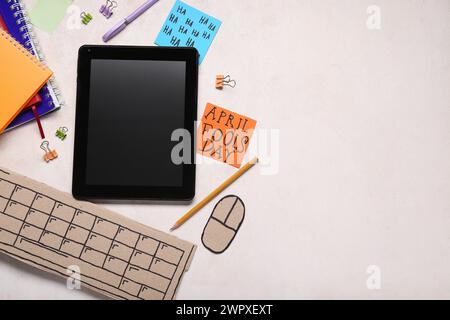 Tablette moderne, clavier d'ordinateur en carton et notes adhésives. Farce du jour des fous d'avril Banque D'Images