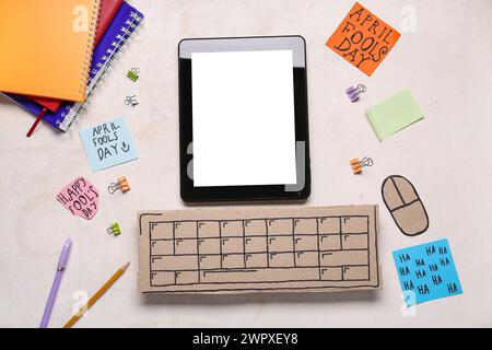 Tablette moderne, clavier d'ordinateur en carton et notes adhésives. Farce du jour des fous d'avril Banque D'Images