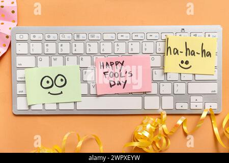 Clavier d'ordinateur et notes adhésives sur fond orange. Farce du jour des fous d'avril Banque D'Images