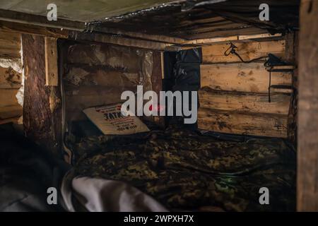 Le lit d'un soldat, sur lequel il y a un oreiller avec le mot "papa" dessus, à l'intérieur d'un blíndage utilisé par une unité d'obusiers L119 de la 80e Brigade d'assaut aérien ukrainienne à un endroit inconnu près de Bakhmut dans le Donbass, Ukraine, le 9 mars 2024. (Photo par /Sipa USA) crédit : Sipa USA/Alamy Live News Banque D'Images