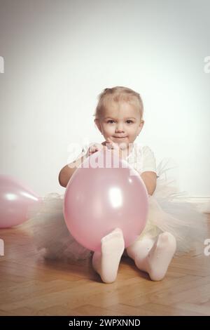 Jolie petite fille de deux ans posant sur plancher de bois pour le portrait Banque D'Images