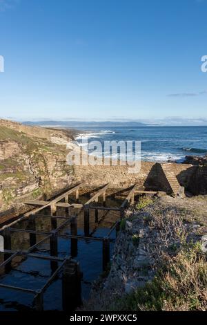 vue panoramique sur la côte avec un terrain rocheux, une vieille structure en pierre, et l'océan sous un ciel clair Banque D'Images