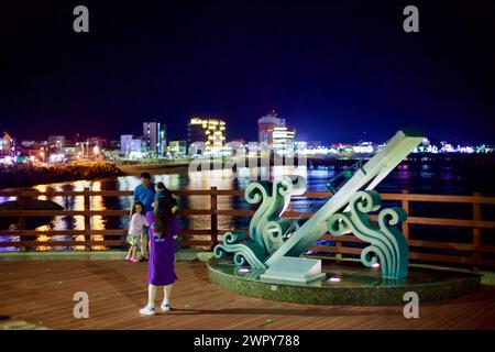 Ville de Sokcho, Corée du Sud - 30 juillet 2019 : une famille prend une photo sur une plate-forme observatoire surplombant la plage de Deungdae la nuit, avec un A. Banque D'Images