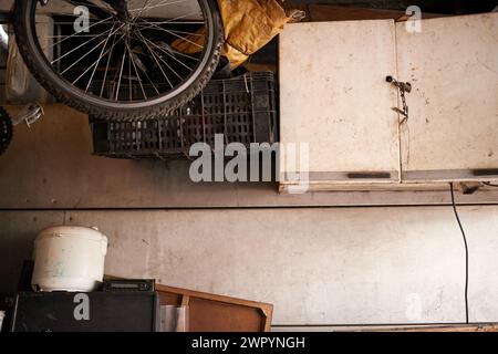 Stockage, vélo et outils dans la maison de hangar avec vieil intérieur en bois et rouille avec des ordures. Maison, garage et vélo dans un bidonville avec meubles ou équipements cassés Banque D'Images