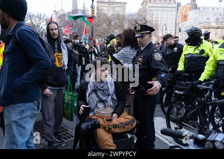Manhattan, États-Unis. 08 mars 2024. Un lieutentant du NYPD fait place à un homme en fauteuil roulant morotisé lors du rassemblement Global Strike for Gaza et de la marche à l'occasion de la Journée internationale de la femme à New York le 9 mars 2024. (Photo de Derek French/SOPA images/SIPA USA) crédit : SIPA USA/Alamy Live News Banque D'Images