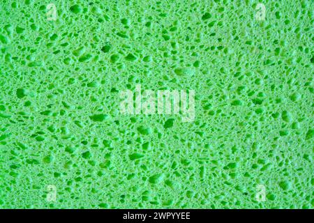 Éponge verte avec fond de texture de pores pour les graphiques. Macro-photo gros plan de tissu éponge domestique. Banque D'Images