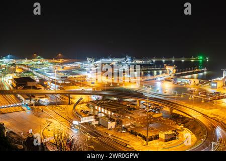 Vue de dessus de falaise regardant vers le bas le complexe de terminal de traversier de voiture occupé au port de Douvres dans le Kent, illuminé la nuit après quelques pluies en hiver. Banque D'Images