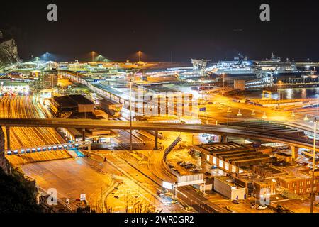 Vue de dessus de falaise regardant vers le bas le complexe de terminal de traversier de voiture occupé au port de Douvres dans le Kent, illuminé la nuit après quelques pluies en hiver. Banque D'Images