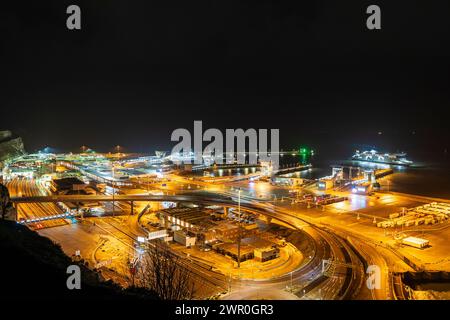 Vue de dessus de falaise regardant vers le bas le complexe de terminal de traversier de voiture occupé au port de Douvres dans le Kent, illuminé la nuit après quelques pluies en hiver. Banque D'Images