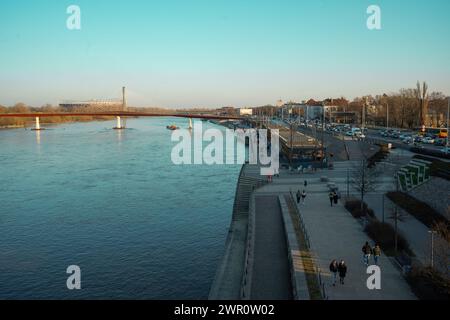 Les gens sont vus marcher le long du boulevard de la Vistule avec le pont piétonnier nouvellement construit visible dans la distance le 09 mars, 2024 à Varsovie, Banque D'Images