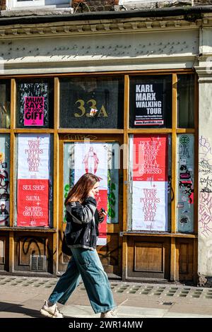 Soho, Londres Royaume-Uni, 08 mars 2024, femme passant devant vide Closed Shop avec des affiches couvrant les fenêtres Banque D'Images