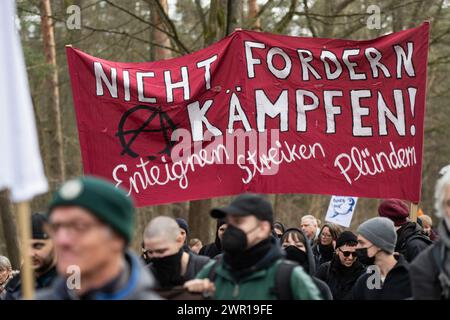 10 mars 2024, Brandebourg, Grünheide : lors d'une manifestation contre l'expansion Tesla sous le slogan 'Tesla No Thanks!', les participants portent une bannière avec l'inscription 'ne demandez pas - combattez! Exproprier Strike Plunder. Photo : Christophe Gateau/dpa Banque D'Images