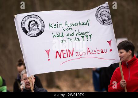 10 mars 2024, Brandebourg, Grünheide : lors d'une manifestation contre l'expansion Tesla sous le slogan 'Tesla No Thanks!', les participants portent une bannière avec l'inscription 'No sell out of Forest and water to Tesla - !No to expansion!'. Photo : Christophe Gateau/dpa Banque D'Images