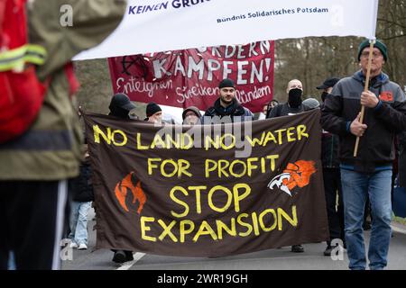 10 mars 2024, Brandebourg, Grünheide : lors d'une manifestation contre l'expansion de Tesla sous le slogan "Tesla non merci!", les participants portent une bannière avec le slogan "pas de terre, pas d'eau pour le profit arrêter l'expansion". Photo : Christophe Gateau/dpa Banque D'Images