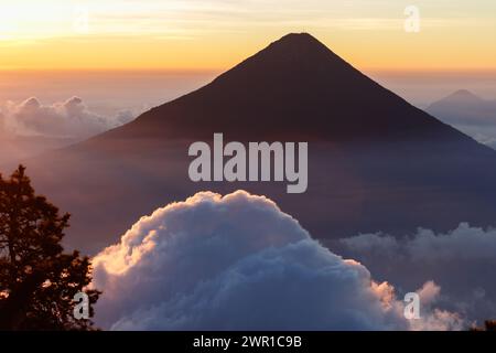 Silhouette du volcan de Agua au lever de soleil orange flamboyant avec des nuages gonflés vus du sommet du volcan de acatenango, guatemala. Banque D'Images