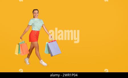 Joyeuse jeune femme hispanique marchant avec des sacs à provisions Banque D'Images