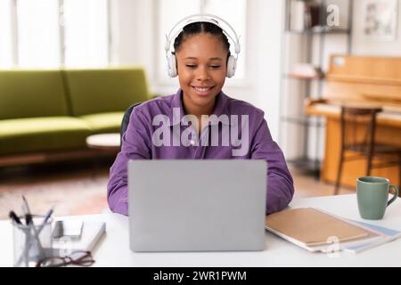 Étudiante noire heureuse dans la classe en ligne, ordinateur portable et écouteurs Banque D'Images
