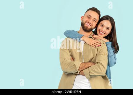 Heureux couple européen jeune serrant tout en posant sur fond bleu Banque D'Images