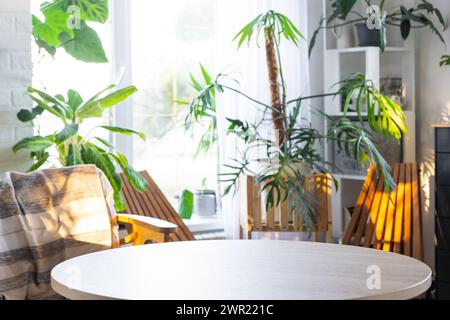 Table ronde vide pour l'installation et la démonstration du produit à l'intérieur avec des plantes tropicales d'intérieur dans la maison verte de pays. Plante d'intérieur cultivant Banque D'Images