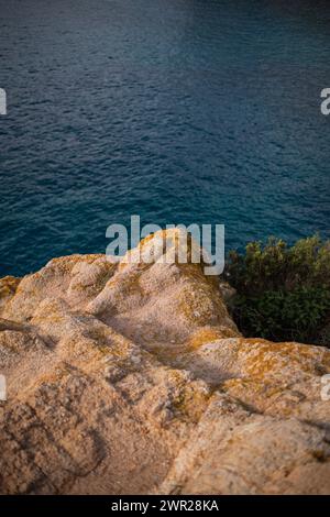 Lichen jaune poussant sur une falaise rocheuse surplombant la mer bleue des Baléares Banque D'Images