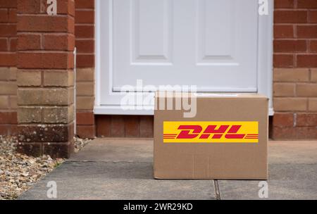 Exeter, UK-10 mars 2024 : une boîte de livraison DHL devant une porte. DHL est une société de logistique allemande qui fournit des services de messagerie, de livraison de colis et de courrier Banque D'Images