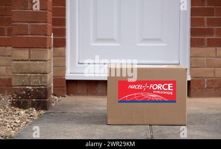 Exeter, UK-10 mars 2024 : une boîte de livraison Parcelforce Worldwide devant une porte. Parcelforce Worldwide est un service de messagerie et de logistique au Royaume-Uni Banque D'Images