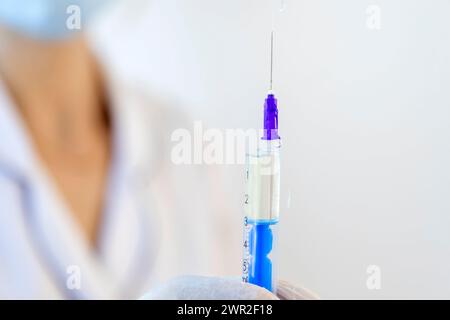 Une femme médecin tient une seringue devant elle, remplie de médicament pour injection. Banque D'Images
