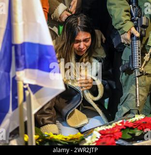 Jérusalem, Israël. 10 mars 2024. Les gens près de la tombe fraîche de Michael Gal qui a été tué dans la guerre de l'épée de fer entre Israël et le Hamas dans le regard. La photo présente une jeune fille pleurant sur la tombe, des fleurs couvrent cela. À sa gauche se trouve le drapeau israélien, et à sa droite un fusil M14 tenu par un soldat. Crédit : Yoram Biberman/Alamy Live News. Banque D'Images