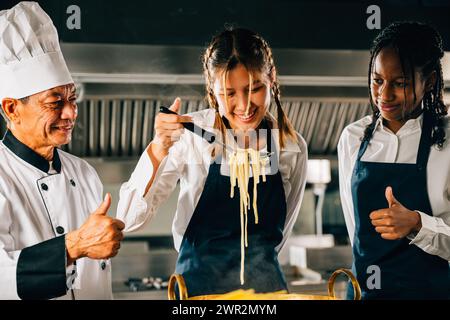 Le chef s'entraîne dans la cuisine. Les écolières cuisinent des nouilles japonaises. Enfants et professeur à poêle. Souriant Banque D'Images