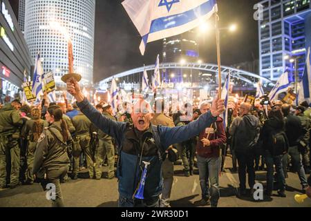 Un manifestant chante alors qu'il tient une torche et agite le drapeau israélien au carrefour de Kaplan pendant la manifestation. Des milliers d’Israéliens ont protesté contre le premier ministre Benjamin Netanyahu et son gouvernement d’extrême droite exigeant la libération immédiate des otages et des élections générales dans l’État d’Israël. Au cours de la manifestation, les manifestants ont franchi les barrières de la police israélienne et des affrontements ont commencé entre la police et les manifestants. Banque D'Images