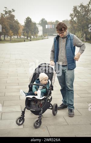 Couple de père et fils en poussette dans le parc d'automne Banque D'Images