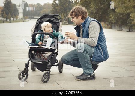 Couple de père et fils en poussette dans le parc d'automne Banque D'Images